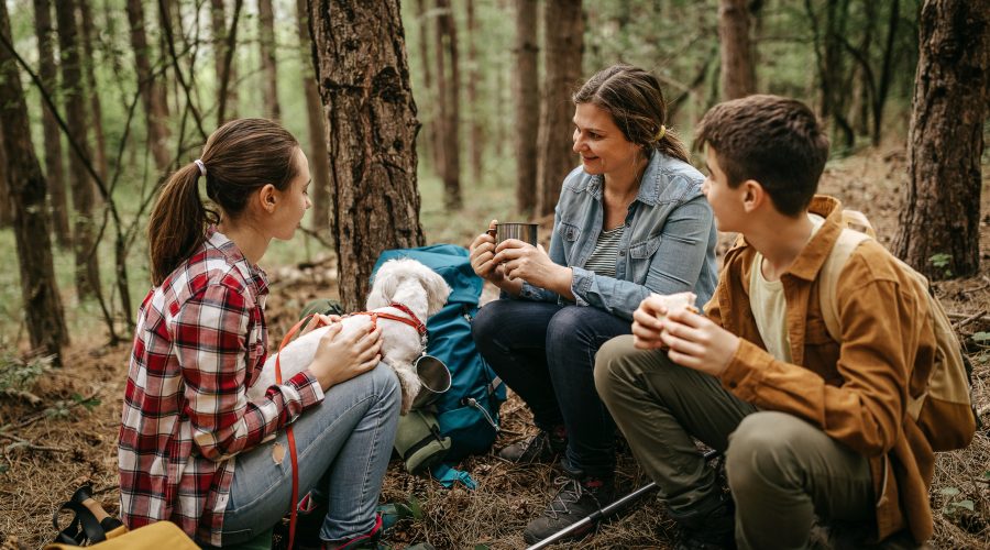 Family with pet dog relaxing while hiking at forest