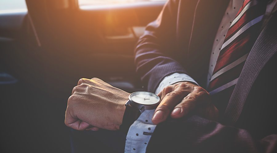 Businessman looking at the time on his wrist watch in car. Business concept.